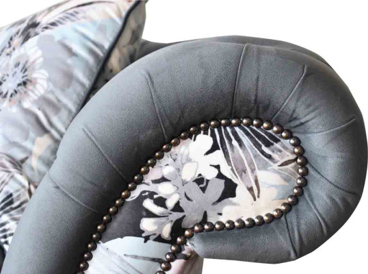 Ein auffälliges Dreisitzer-Sofa im Chesterfield-Design mit zarter grauer Blumendekoration